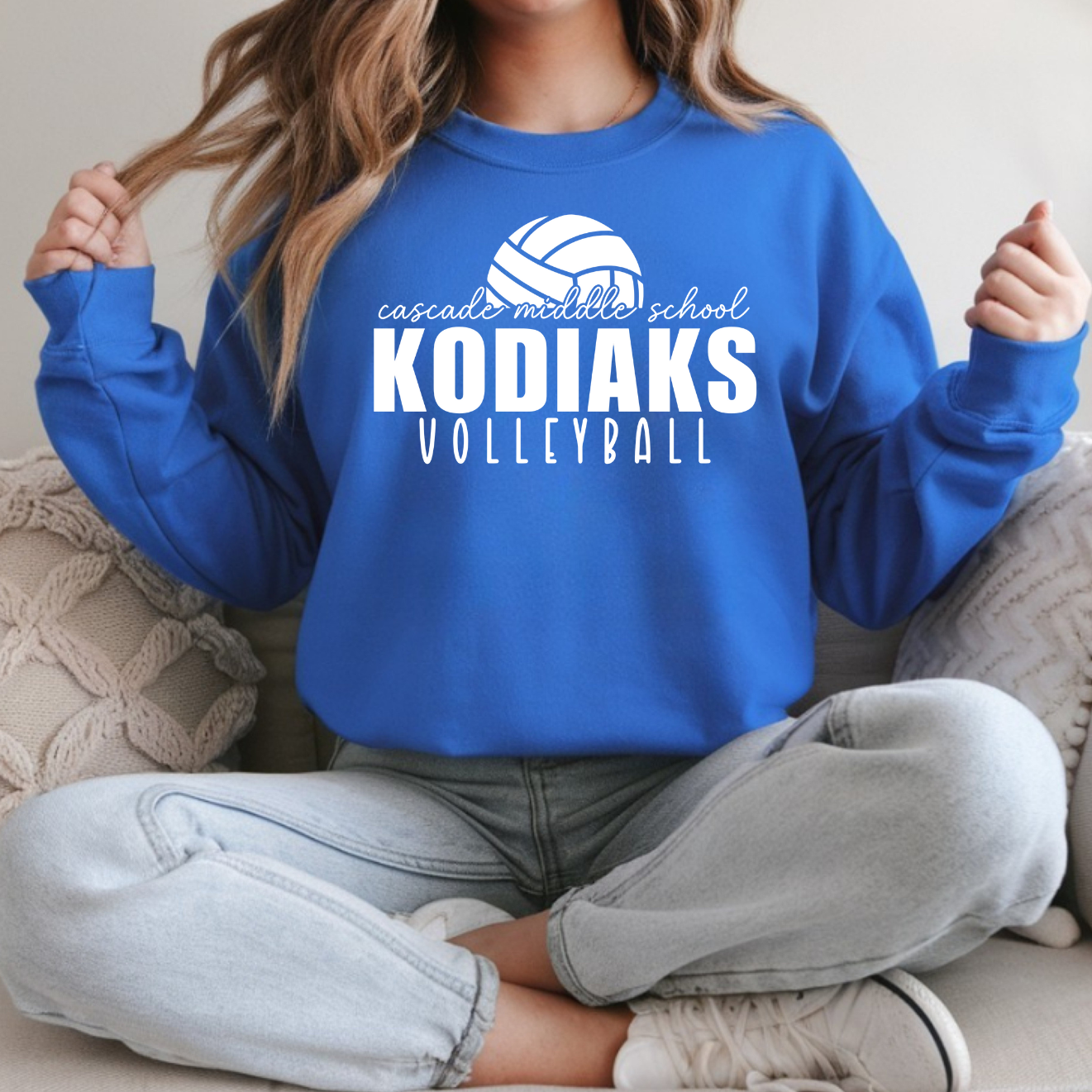 Person wearing a blue 'Kodiaks Volleyball' sweatshirt sitting on a couch.
